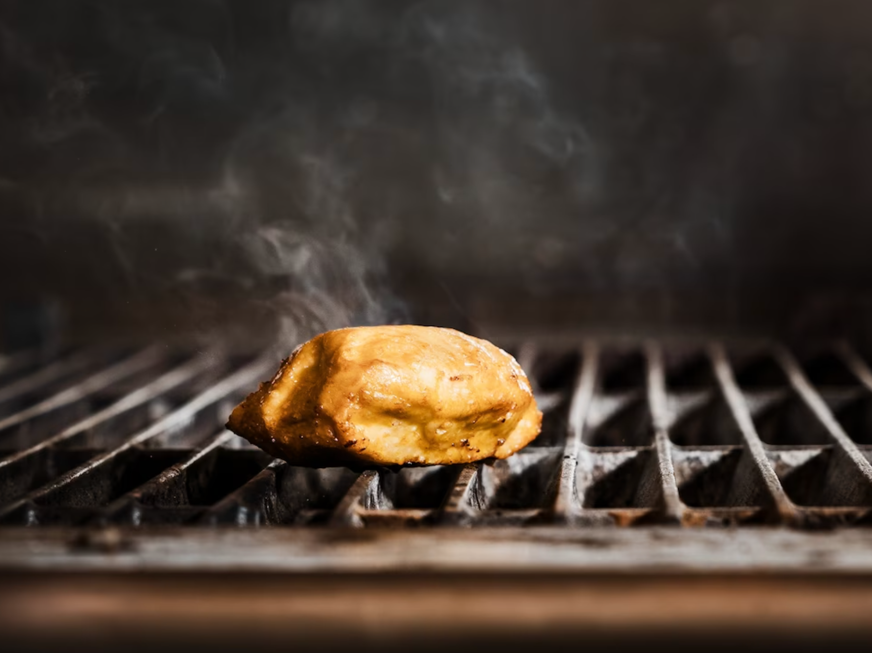 a piece of cultivated chicken steaming on a grill