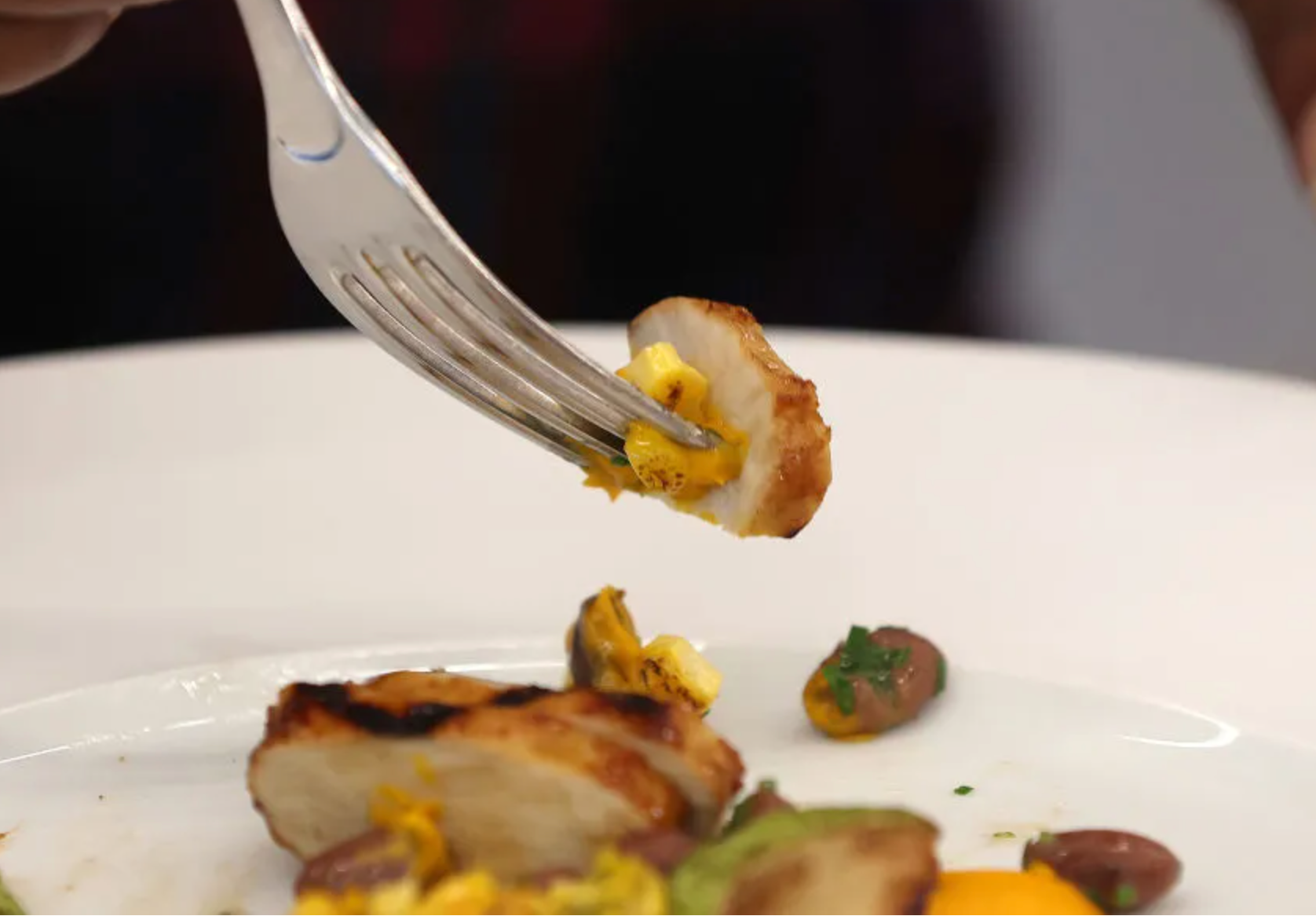 a fork picking up lab grown meat from a plate