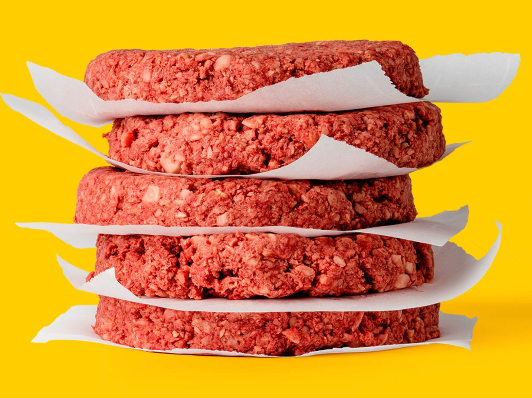 stack of plant burgers against yellow background