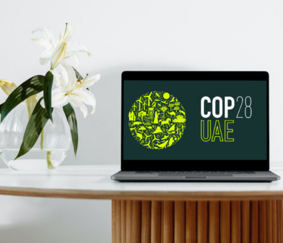 A vase of flowers and a laptop with the COP28 logo