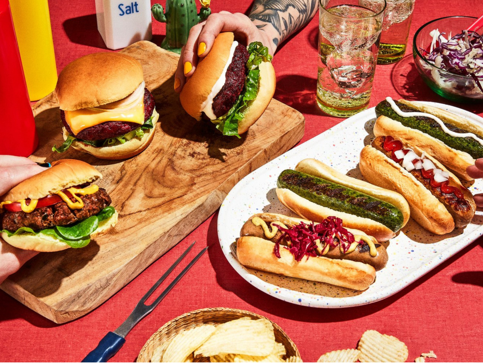 a table set with hot dogs and burgers, some brown and some noticeably green
