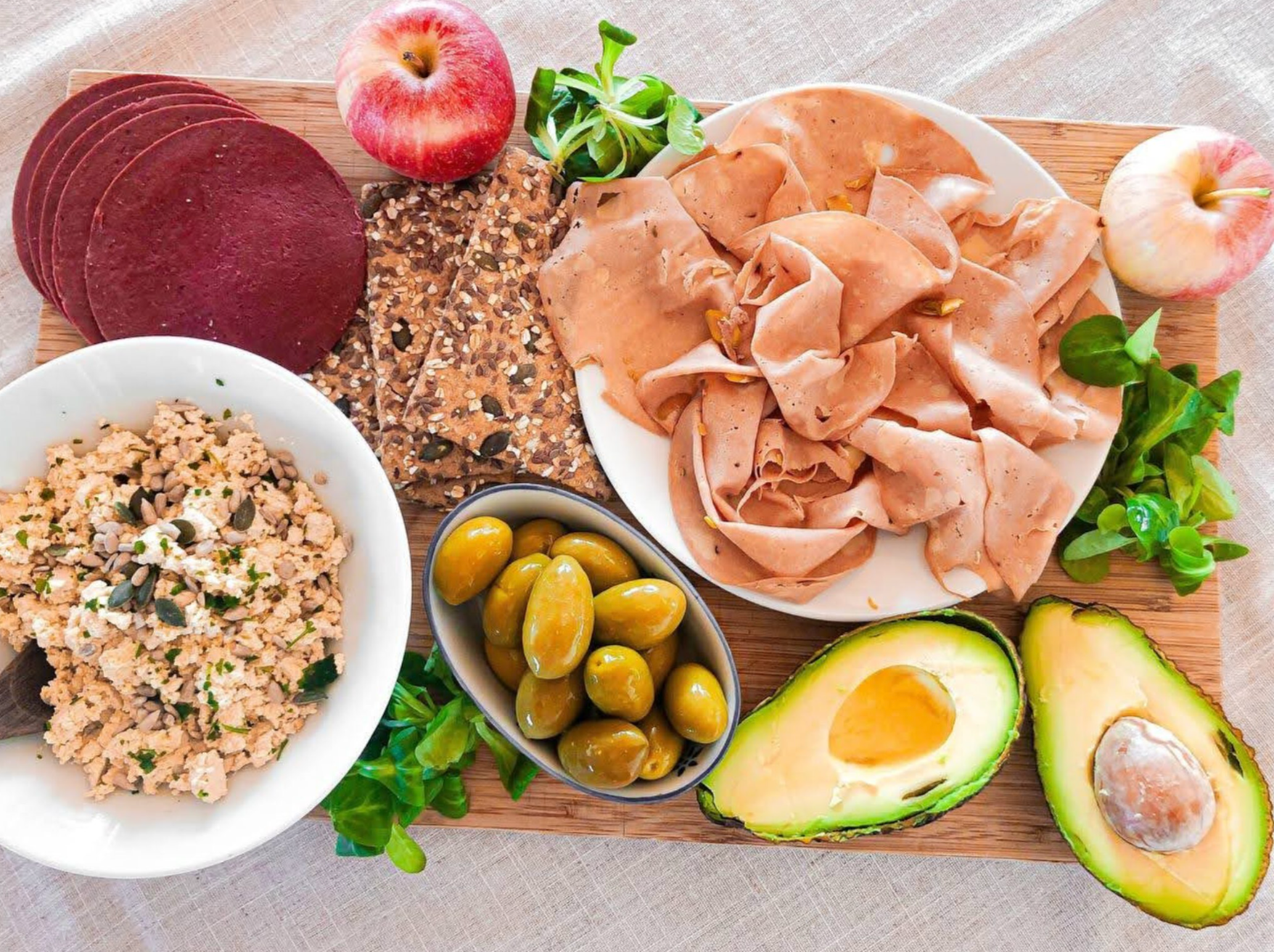 spread of plant meats with avocado, olives, and apple