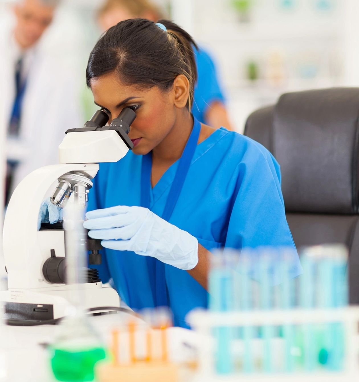 a female scientist looking through a microscope in a lab
