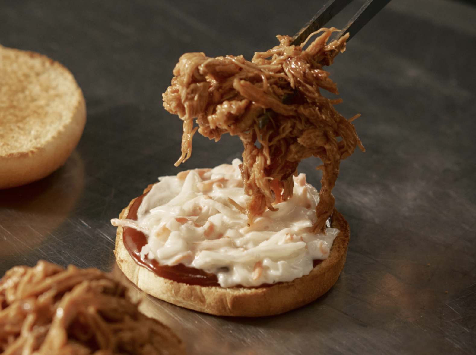 plant-based pulled pork being put on a slider bun with chopsticks